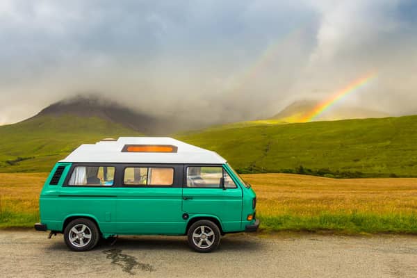 An old green camper van in the shadow of the misty Cuillin mountains and a rainbow, at Glen Brittle on the Isle of Skye, Scotland