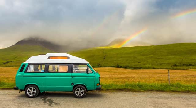 An old green camper van in the shadow of the misty Cuillin mountains and a rainbow, at Glen Brittle on the Isle of Skye, Scotland