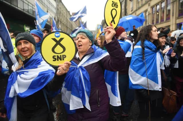 Pro-independence protesters hold up Scottish National Party (SNP) emblems as they join a march organised by the grassroots organistaion All Under One Banner calling for Scottish independence in Glasgow in 2020
