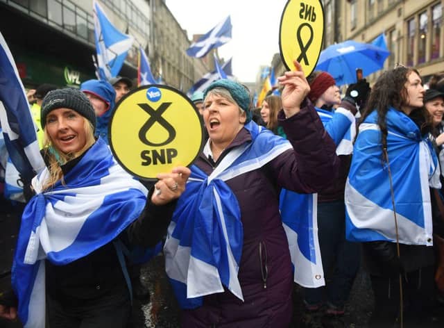 Pro-independence protesters hold up Scottish National Party (SNP) emblems as they join a march organised by the grassroots organistaion All Under One Banner calling for Scottish independence in Glasgow in 2020