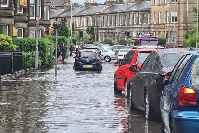 Pedestrians watching a fire engine driving slowly through the flooded streets of Stockbridge, Edinburgh, after heavy rainfall batters parts of the city.
