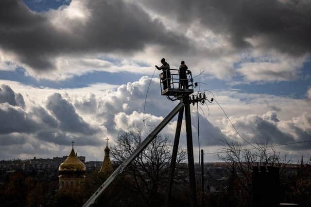 Workers repair power lines cut by shelling in the town of Kupiansk, Kharkiv region, which was formerly occupied by Russian forces.