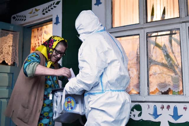 How voting can take place amid the Covid pandemic: an official in full PPE holds a mobile ballot box as a woman casts her vote in Moldova's presidential election in the village of Stetcani (Picture: Sergei Gapon/AFP via Getty Images)