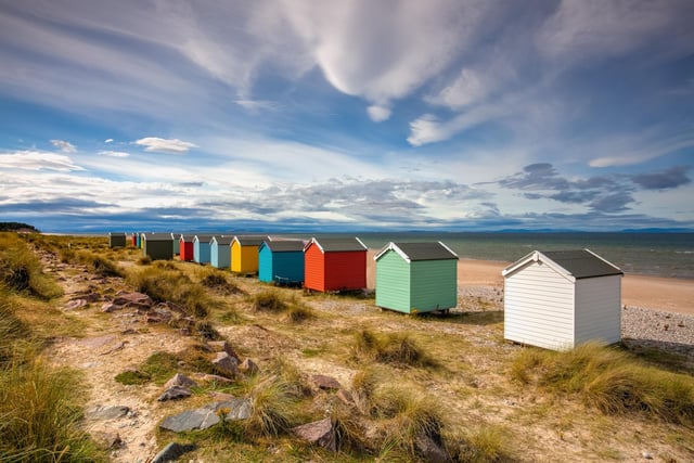 Colourful wooden beach huts line the shore at Findhorn beach, on the Moray coast