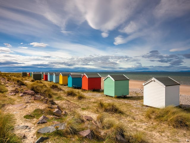 Colourful wooden beach huts line the shore at Findhorn beach, on the Moray coast