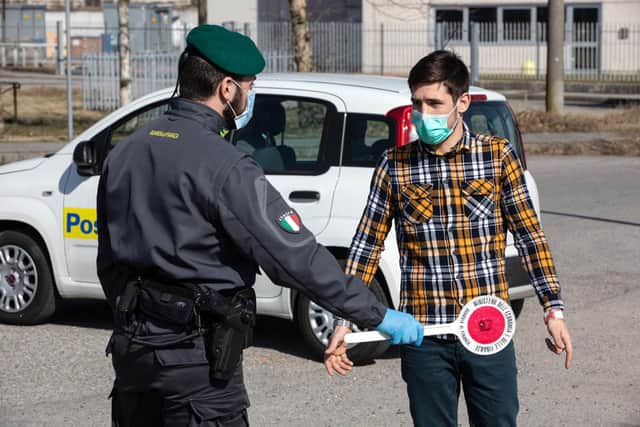 An Italian Guardia di Finanza (Custom Police) officer, wearing a respiratory mask, talks to a young man at a road block on February 24, 2020 in Casalpusterlengo, south-west Milan, Italy.