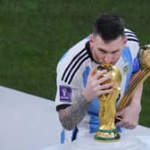 Argentina's Lionel Messi, holding the Golden Ball award for best player of the tournament, kisses the World Cup trophy.