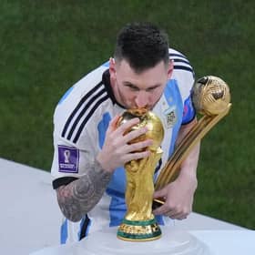 Argentina's Lionel Messi, holding the Golden Ball award for best player of the tournament, kisses the World Cup trophy.