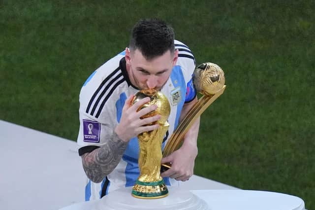 Argentina's Lionel Messi, holding the Golden Ball award for best player of the tournament, kisses the World Cup trophy.