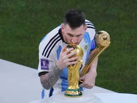 Argentina's Lionel Messi, holding the Golden Ball award for best player of the tournament, kisses the World Cup trophy.