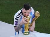 Argentina's Lionel Messi, holding the Golden Ball award for best player of the tournament, kisses the World Cup trophy.