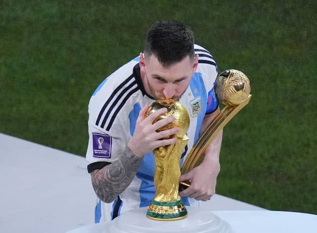 Argentina's Lionel Messi, holding the Golden Ball award for best player of the tournament, kisses the World Cup trophy.