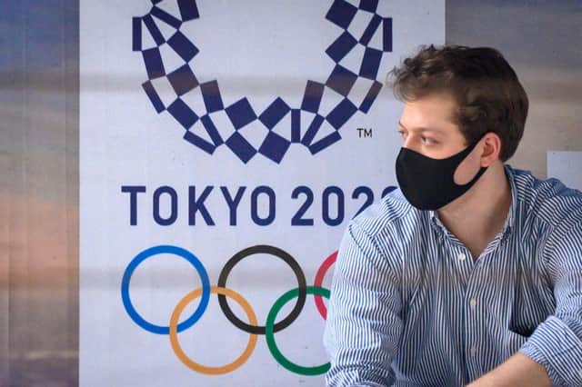 A man wearing a facemask, amid concerns over the spread of the COVID-19 coronavirus, sits at a bus stop in front of a Tokyo 2020 Olympics advertisement. Picture: Getty