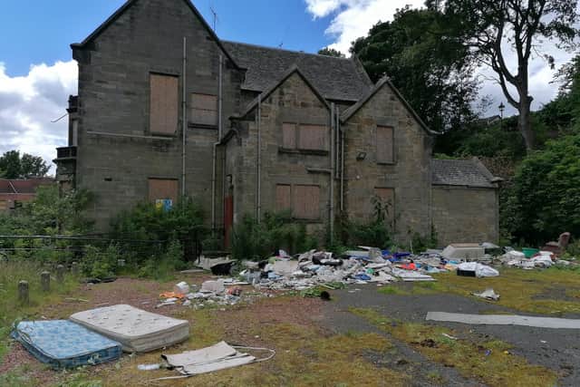 The Priory building at the former Priory Campus, Kirkcaldy. The side of the building is now covered with debris including mattresses, bags of rubbish, an upturned bathtub and an armchair.