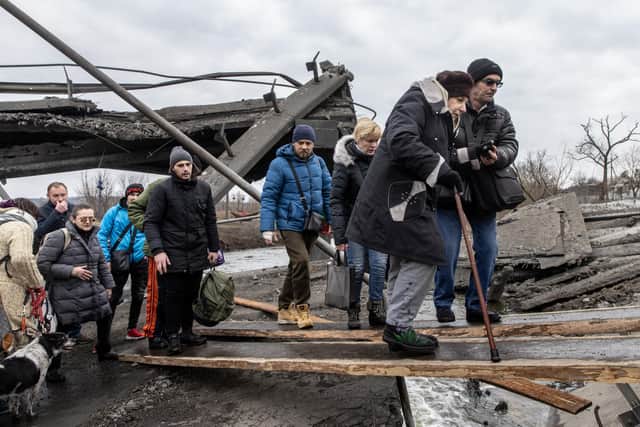 Residents of Irpin, Ukraine, flee heavy fighting via a destroyed bridge as Russian forces enter the city on Monday (Picture: Chris McGrath/Getty Images)