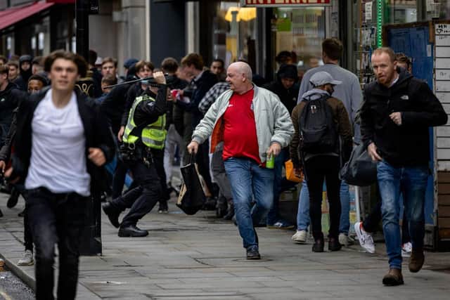 A policeman tackles a group of England fans as they attempt to run towards Scotland fans gathered in Leicester Square on June 18, 2021 in London. (Credit: Rob Pinney/Getty Images)