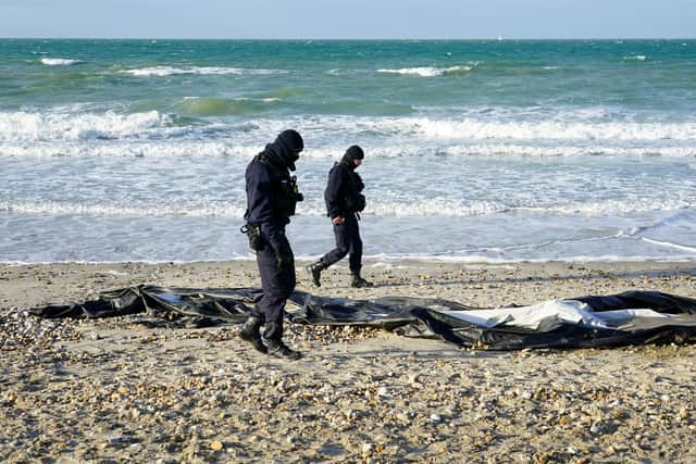 French police officers pass a deflated dinghy on the beach in Wimereux near Calais as migrants continue to launch small boats along the coastline in a bid to cross the Channel towards the UK.