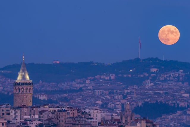 A full moon rises behind the Galata tower in Turkey.