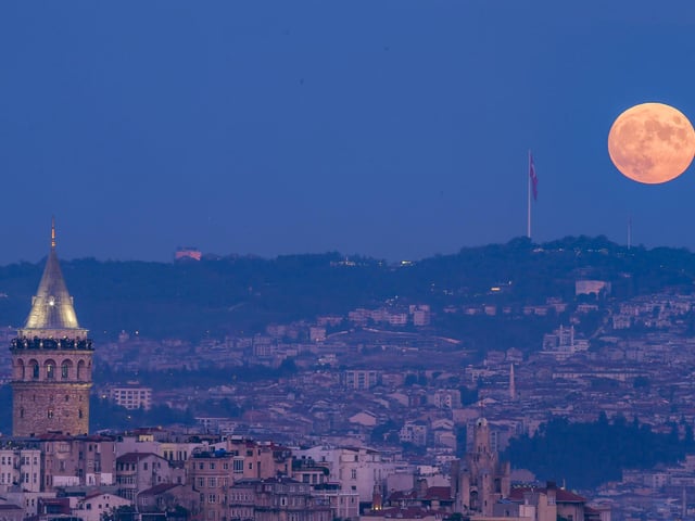 A full moon rises behind the Galata tower in Turkey.