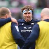 Jamie Ritchie of Scotland looks on as players of Scotland huddle against Ireland.