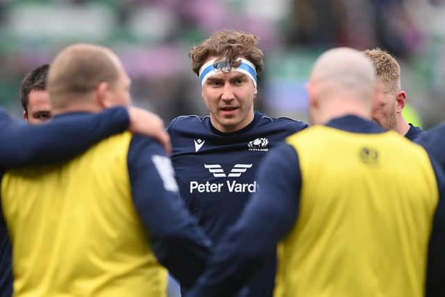 Jamie Ritchie of Scotland looks on as players of Scotland huddle against Ireland.