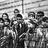 A group of child survivors behind a barbed wire fence at the Auschwitz-Birkenau concentration camp, on the day it was liberated by Soviet soldiers, January 27, 1945 (Picture: Alexander Vorontsov/Keystone/Hulton Archive/Getty Images)