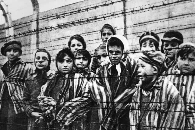 A group of child survivors behind a barbed wire fence at the Auschwitz-Birkenau concentration camp, on the day it was liberated by Soviet soldiers, January 27, 1945 (Picture: Alexander Vorontsov/Keystone/Hulton Archive/Getty Images)