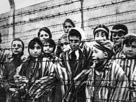 A group of child survivors behind a barbed wire fence at the Auschwitz-Birkenau concentration camp, on the day it was liberated by Soviet soldiers, January 27, 1945 (Picture: Alexander Vorontsov/Keystone/Hulton Archive/Getty Images)