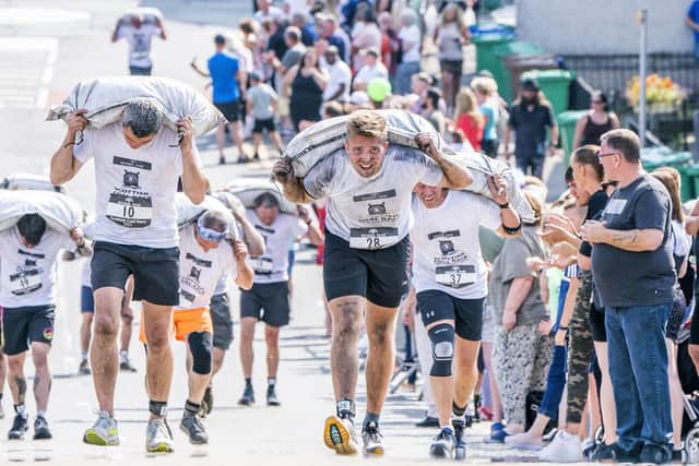 Competitors take part in the Scottish Coal Carrying Championships through the streets of Kelty in Fife. Picture date: Saturday August 28, 2021. PA Photo. The annual event is one of only two Coal Races in the world and the men's race requires participants to carry a 50-kilo bag of coal and the women's race requires a 25-kilo bag of coal to be carried over 1000 metres through the village. Photo credit should read: Jane Barlow/PA Wire