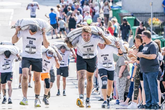 Competitors take part in the Scottish Coal Carrying Championships through the streets of Kelty in Fife.  Picture date: Saturday August 28, 2021. PA Photo. The annual event is one of only two Coal Races in the world and the men's race requires participants to carry a 50-kilo bag of coal and the women's race requires a 25-kilo bag of coal to be carried over 1000 metres through the village. Photo credit should read: Jane Barlow/PA Wire 