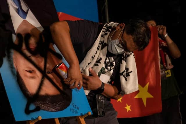 Demonstrators in Taiwanese capital Taipei spray paint over an upside-down portrait of Chinese leader Xi Jinping during an anti-China protest