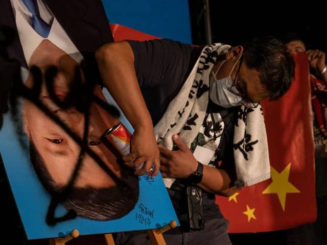 Demonstrators in Taiwanese capital Taipei spray paint over an upside-down portrait of Chinese leader Xi Jinping during an anti-China protest
