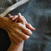 A terminally-ill resident holds a health worker's hand. Picture: Getty Images