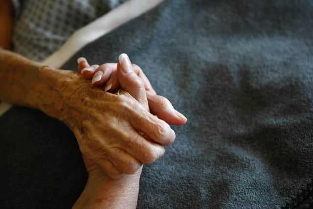 A terminally-ill resident holds a health worker's hand. Picture: Getty Images