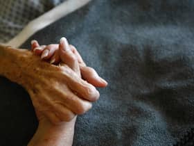 A terminally-ill resident holds a health worker's hand. Picture: Getty Images