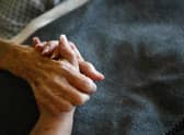 A terminally-ill resident holds a health worker's hand. Picture: Getty Images