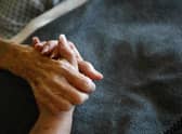 A terminally-ill resident holds a health worker's hand. Picture: Getty Images