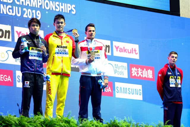 Duncan Scott, right, stands apart from the other medallists during a photo-shoot on the podium at the 2019 swimming World Championships in South Korea. Scott, who won bronze, was protesting against gold medallist Sun Yang in a stance for clean sport.