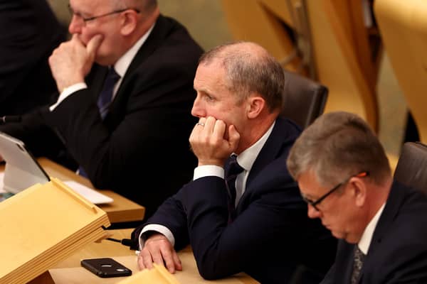 Former Cabinet Secretary for Health and Social Care Michael Matheson listens to First Minister John Swinney in the Scottish Parliament.