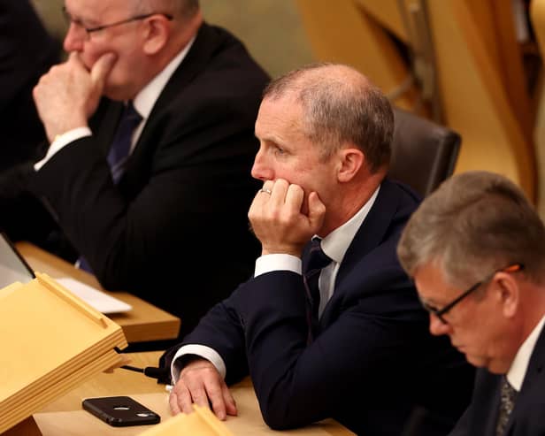 Former Cabinet Secretary for Health and Social Care Michael Matheson listens to First Minister John Swinney in the Scottish Parliament.