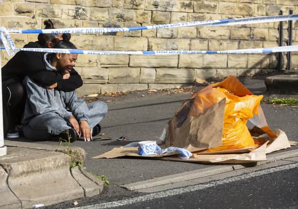 Two grieving women visit the scene where a boy was stabbed yesterday outside of North Huddersfield Trust School.