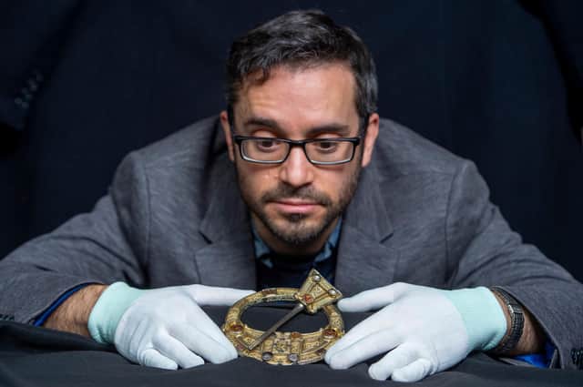 Dr Adrian Maldonado, Glenmorangie Research Fellow at National Museums Scotland, with the Hunterston Brooch, one of the museum's most prized medieval objects which features on the cover of a new book, Crucible of Nations: Scotland from Viking Age to Medieval Kingdom. The brooch was made around 700AD, using extremely sophisticated Irish-Scottish metalworking techniques. Some 200 years later, a Viking runic inscription was added of the Gaelic name Melbrigda. [image credit: Neil Hanna]"