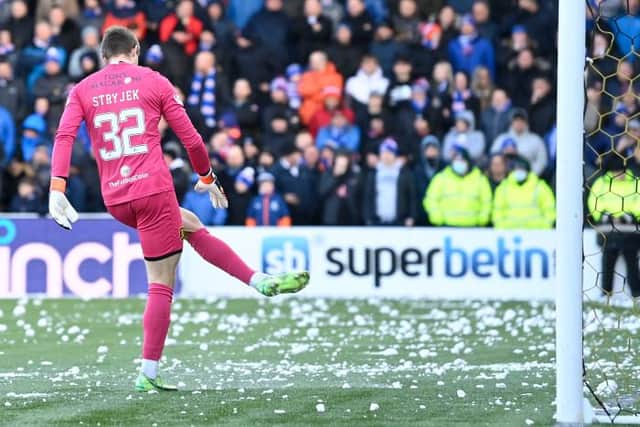 Livingston goalkeeper Max Stryjek tries to clear snowballs from his penalty area as the start of the second half of the match against Rangers is delayed. (Photo by Rob Casey / SNS Group)
