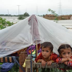 Children shelter from the rain under a plastic sheet near their collapsed house in Jaffarabad district, Balochistan province, after heavy monsoon rainfalls caused major flooding across much of Pakistan (Picture: Fida Hussain/AFP via Getty Images)