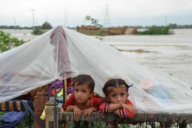 Children shelter from the rain under a plastic sheet near their collapsed house in Jaffarabad district, Balochistan province, after heavy monsoon rainfalls caused major flooding across much of Pakistan (Picture: Fida Hussain/AFP via Getty Images)