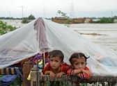 Children shelter from the rain under a plastic sheet near their collapsed house in Jaffarabad district, Balochistan province, after heavy monsoon rainfalls caused major flooding across much of Pakistan (Picture: Fida Hussain/AFP via Getty Images)