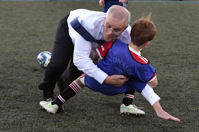Australia's Prime Minister Scott Morrison crash tackles a child during a game of soccer.