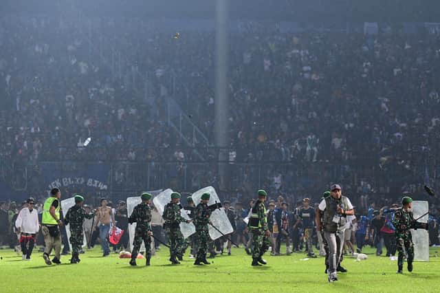 Members of the Indonesian army securing the pitch after a football match between Arema FC and Persebaya Surabaya at Kanjuruhan stadium in Malang