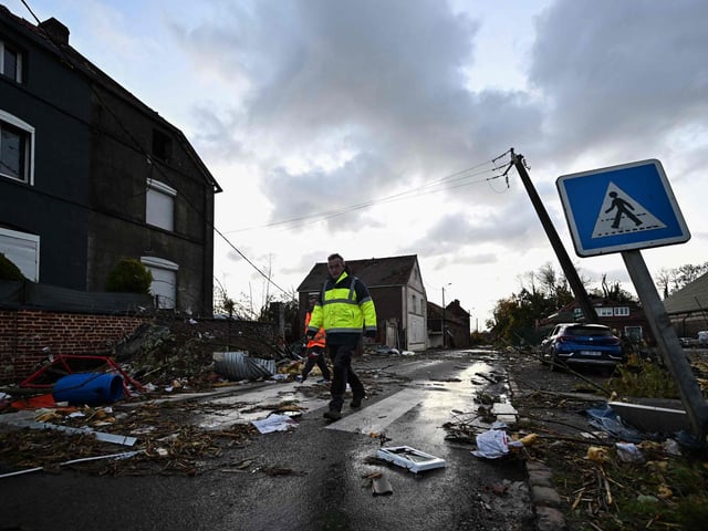 Municipal workers walk past damages in Bihucourt, northern France, on October 24, 2022 after a tornado hit the region. (Photo by Sameer Al-Doumy / AFP)