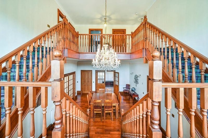 The grand reception hall featuring a chandelier and staircase leads onto a living room, kitchen, office, two bedrooms, plus an annexed living room and kitchen.
